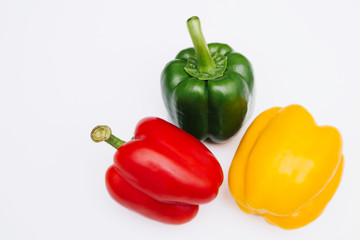 Sweet pepper multicolored on a white background. Red, yellow and green peppers lie on a light table. Bright vegetable isolate