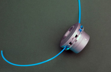 New metal reel for a lawn mower with a plastic blue line on a grey background.