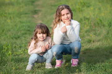 Fototapeta premium little sisters walk in the park at sunset