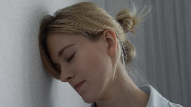 Upset woman standing near wall, victim of domestic violence, relations problems