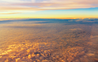 Top view of fluffy clouds on sunset sky view from flying airplane window