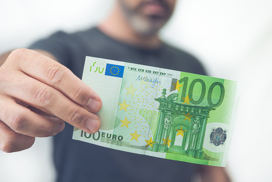 Mann hält 100 Euro Schein in der Hand