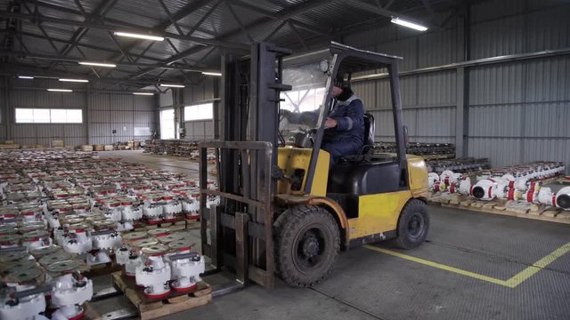 Teamwork male person industry production, using machine work and vehicle, delivering merchandise for transnational export. Oil and Gas Wellhead tree equipment production plant on pallets in warehouse.