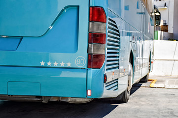 Rear side of a parked light blue coach 