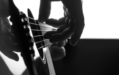 Fingers on a strings acoustic guitar close up