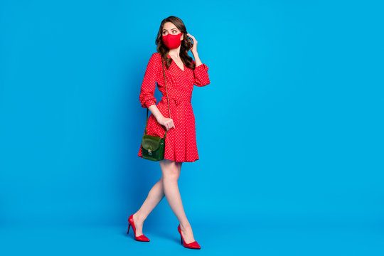 Full size profile photo of beautiful lady keep social distance avoid people walk outdoors breathe air bored stay home wear red dress stilettos clutch face mask isolated blue color background