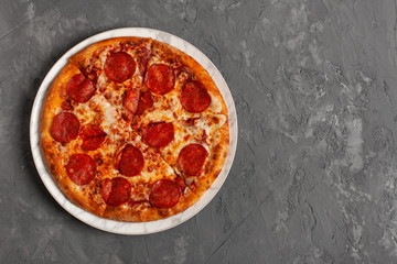 Tasty pizza. Pepperoni pizza on grey concrete background with copy space. Top view of slice pepperoni pizza. 
