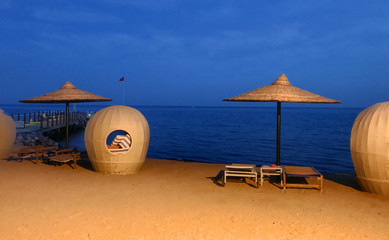 Yellow-lit beach furniture towards a heavy blue ocean background