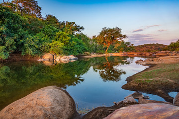 Dusk near river with large boulders in Africa