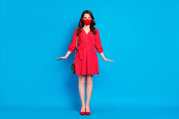 Full length photo of pretty lady keep social distance people walk outside breathe air wear dotted red short dress stilettos clutch bag protective facial mask isolated blue color background