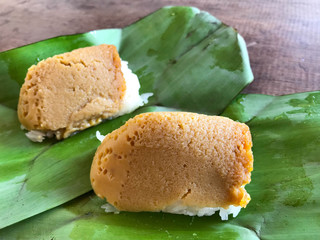 'Khao Niao Sangkhaya' Thai dessert sticky rice with egg custard wrapped in green banana leaf on wooden  background. Thai sweet dessert.