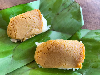 'Khao Niao Sangkhaya' Thai dessert sticky rice with egg custard wrapped in green banana leaf on wooden  background. Thai sweet dessert.