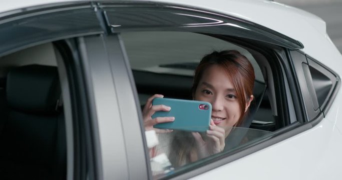 Woman use of mobile phone take photo and sit inside car