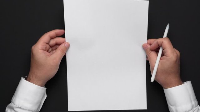 top view of a blank sheet of paper and a businessman's hands on a black table, white shirt and wrist watch