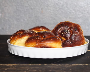 Homemade cake.Buns sprinkled with sesame and sugar syrup on a dark wooden table with a gray background.
