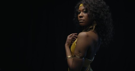 Gorgeous black woman is posing in gold dress and jewelry, black background, 4k