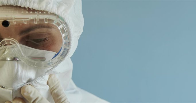 Doctor in protective suit with face mask, eyeglasses and gloves portrait. Nurse in protective suit with face mask, eyeglasses and gloves. Woman wearing protection suite. Copyspace