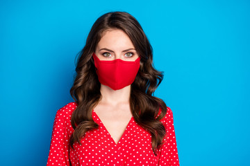 Closeup photo of nice pretty millennial curly lady responsible citizen dressed dotted red shirt blouse dress protective facial respiratory mask isolated blue color background