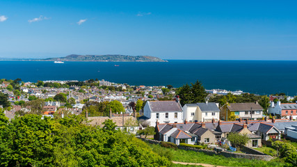 Fototapeta na wymiar Dalkey village houses as seen from the hill top with the Howth peninsula on the horizon. Sunny summer day in Dublin, Ireland.