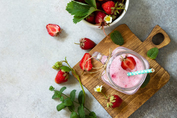 Natural detox, fruit dessert, healthy dieting concept. Strawberry fruit Yogurt smoothie or milk shake in glass jar on a light stone or slate table. Top view flat lay background. Copy space.