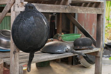 Iron frying pan is hung on brown wooden table.