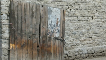 Crooked wooden door with grey brick wall