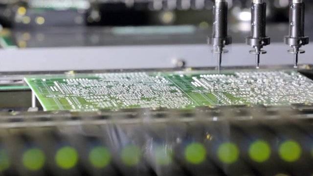 Close-up view of automated industrial equipment making electronic circuit board. Industry machinery working on components for hi tech products