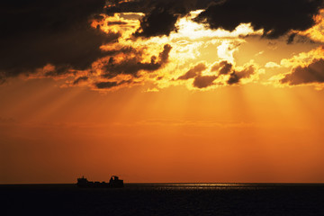 Obraz na płótnie Canvas Golden hour above baltic sea and silhouette of cargo ship on horizon