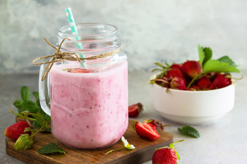 Natural detox, fruit dessert, healthy dieting concept. Strawberry fruit Yogurt smoothie or milk shake in glass jar on a light stone or slate table.