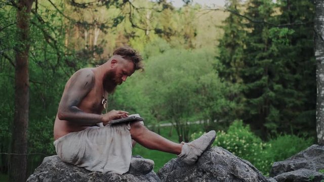 Wild Primitive Savage Dancing with Modern Tablet PC or Mobile Computer in Forest. Interacting, Playing game, Listening to Music and Pretend to Be Popular DJ. Digitalization, Internet Technology.
