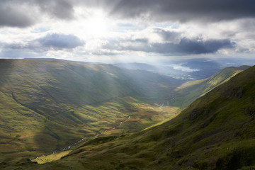 Sunshine breaking through the cloud over Rydal Beck with Lake Windermere and Ambleside in the distance in the Lake District.