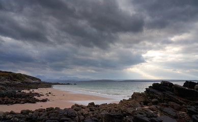 Fototapeta na wymiar Rays of autumn sunlight breaking through the cloud at the beach of Big Sand near Gairloch with distand views of the torridon mountains in the Scottish Highlands, Scotland, UK.