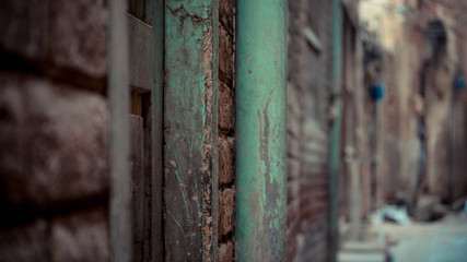 Green rusty pole mounted on the brick wall