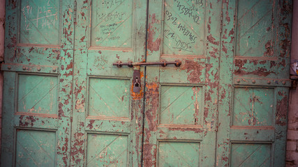 grren metal door with rust and a lock attached