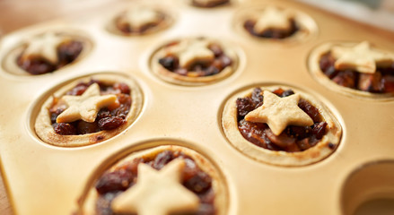 Freshly baked Christmas mince pies in golden baking tray.