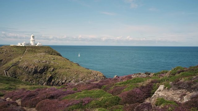 Yacht sailing past Strumble Head Lighthouse Fishguard Pembrokeshire Wales 