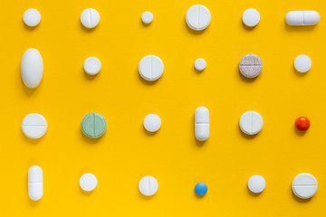 .Medical white pills on a yellow background. Pharmaceutical concept