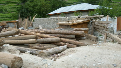 Logs of wood next to a stone wall with blue rooftops