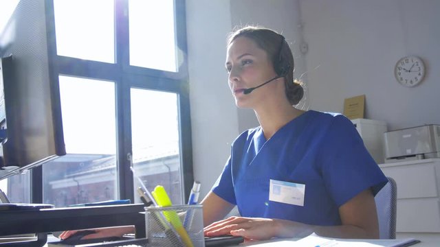 medicine, technology and healthcare concept - female doctor or nurse with headset and computer working at hospital