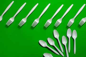 eco-friendly disposable tableware on a green background. isolate. corn starch spoons and forks. biodegradable dishes. natural materials for replacing plastic. place for text