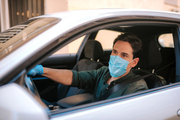 Fototapeta na wymiar a man driving a car puts on a medical mask during an epidemic, protection from the virus