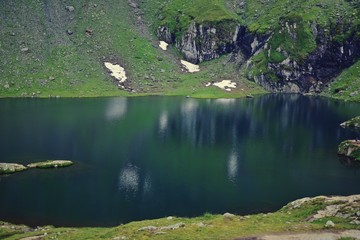 glacier lake at the mountain in summer time with clouds