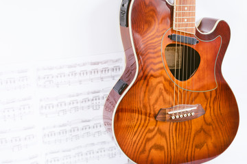 Obraz na płótnie Canvas acoustic guitar on sheet music and white background