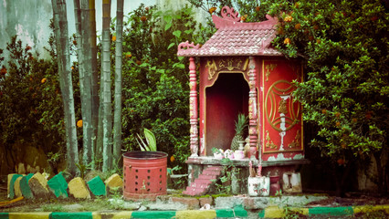 Small red temple with a red bucket with holes