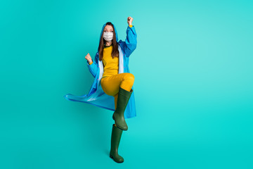 Full length photo of pretty lady rainy weather use medical infection flu mask raise fists leg celebrate quarantine ending wear raincoat sweater pants gumboots isolated teal color background