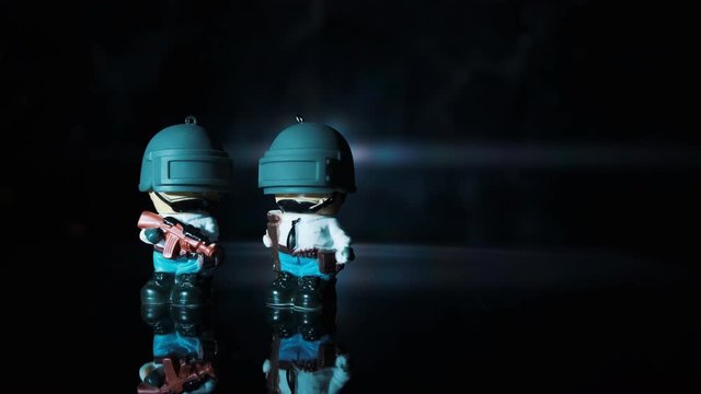 Two little man from the game with a rifle stands on a table against the color background