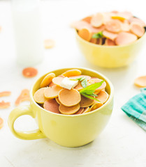 Mini pancake cereal in light green mug, white concrete background ready to serve on breakfast. New food trend during covid-19. Copy space for text. Butter and mint leaves, milk, checkered aqua cloth