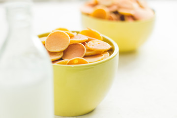 Mini pancake cereal in light green mug on white concrete background ready to serve on breakfast with milk bottle. New food trend during covid-19 lockdown. Copy space for text. Macro close up shoot