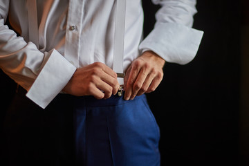 the groom puts on his wedding suit in preparation for the wedding ceremony