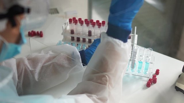 Laboratory assistant is holding a pipette dispenser for working with reagents. The study of blood samples infected with the virus covid-19. Search for a vaccine, blood serological analysis